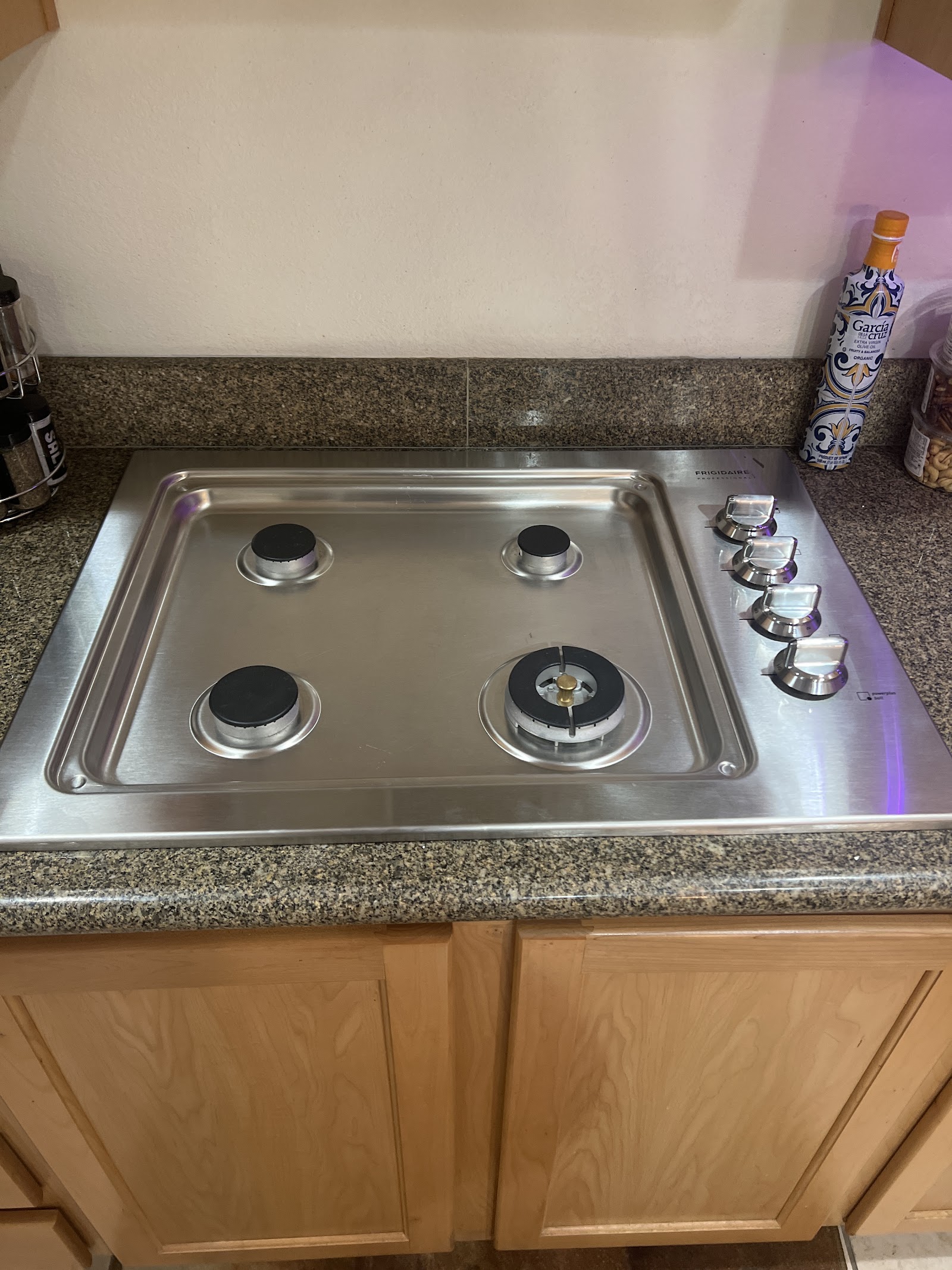 Stainless steel Frigidaire Professional four-burner gas cooktop installed in a granite counter