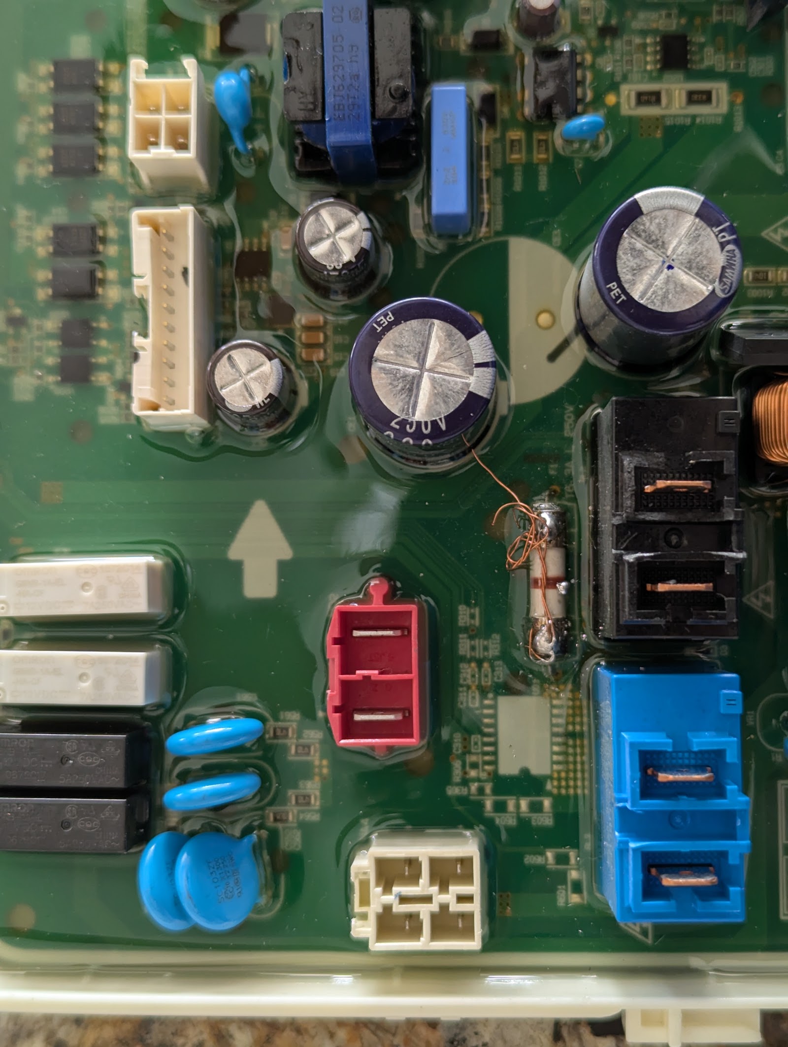 Close-up of an appliance control board with capacitors and connectors