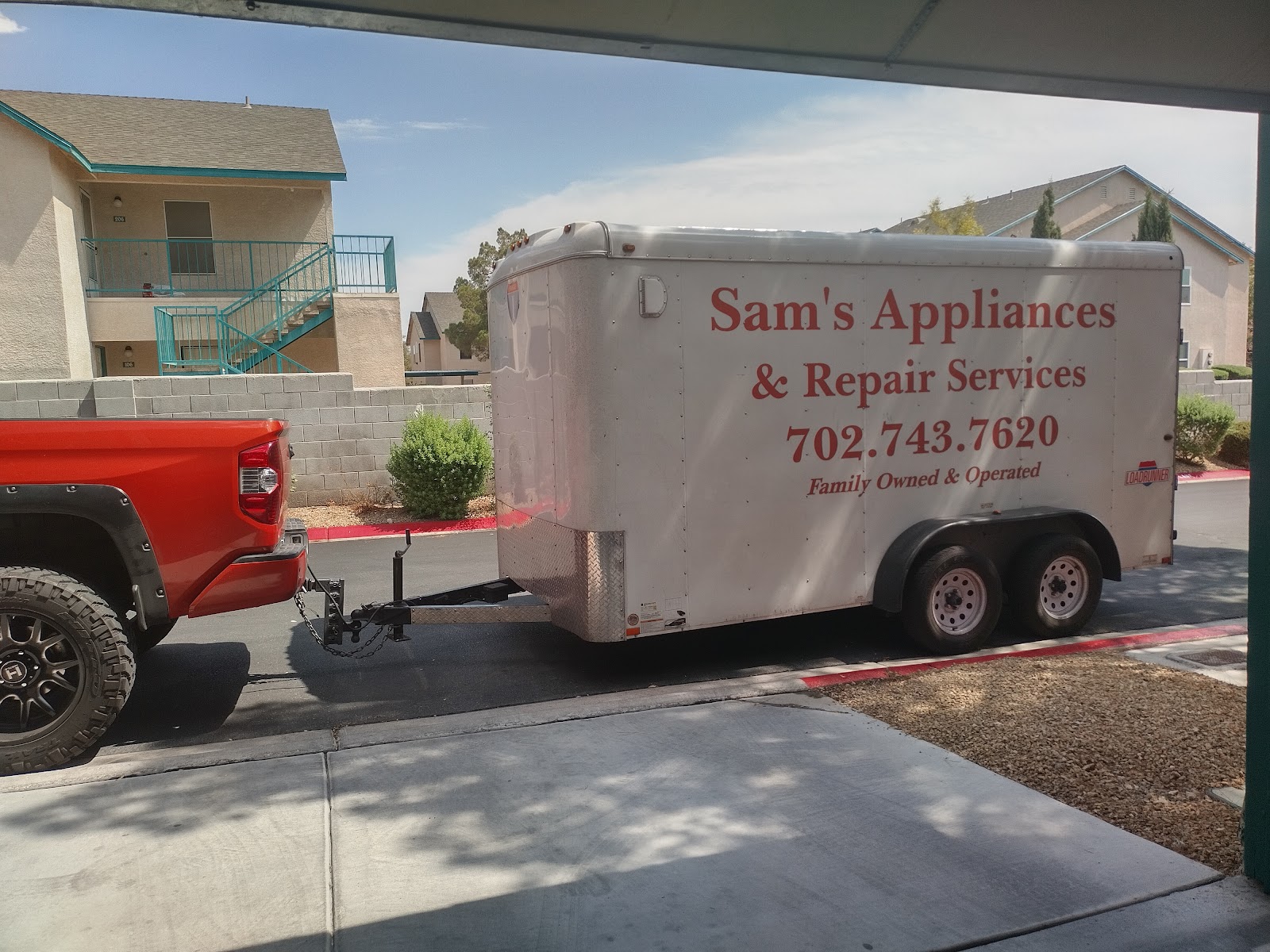 Red pickup truck towing an enclosed trailer branded Sam's Appliances & Repair Services